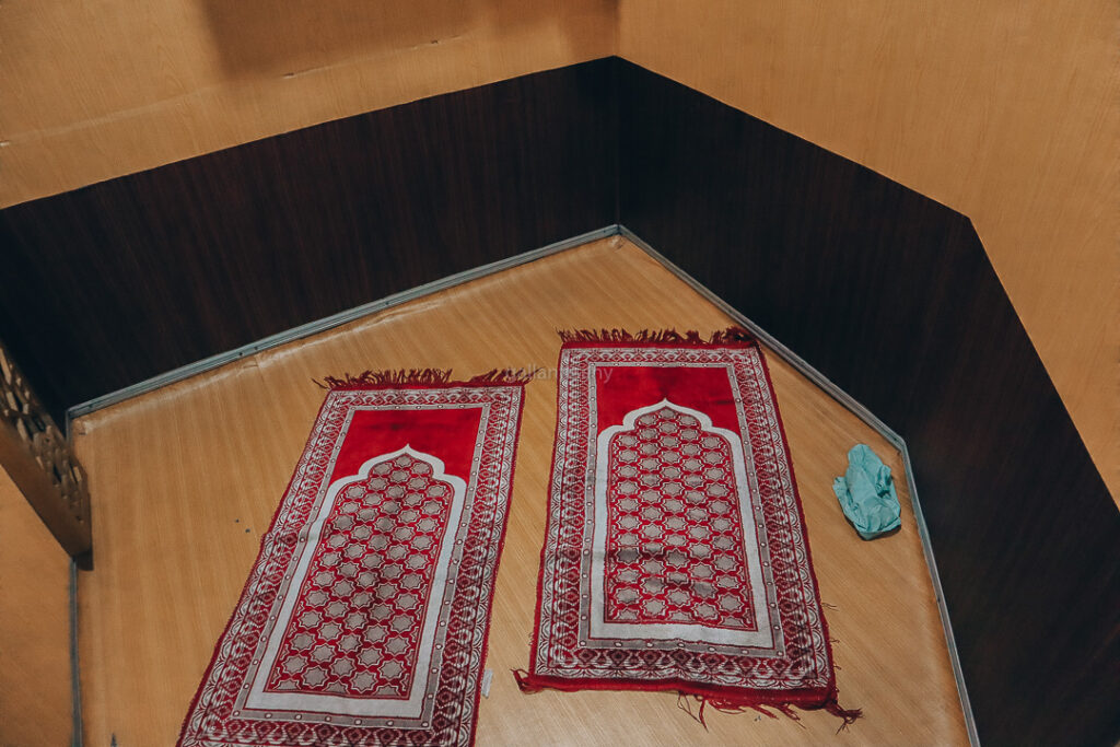 Ruang Salat di Kereta Makan KA Sangkuriang. Terdapat dua sajadah berwarna merah dengan lantai menggunakan lapisan seperti kertas berwarna coklat menyerupai kayu
